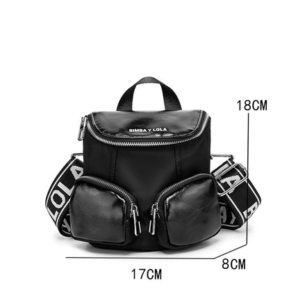 A modern mini backpack-inspired crossbody bag designed for everyday convenience. Crafted from durable black nylon with multiple front pockets and bold logo straps, it combines street-style aesthetics with practical storage